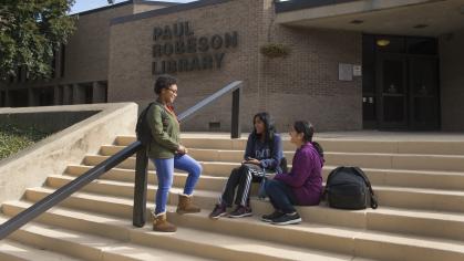 Students talk on the steps of the Paul Robeson Library at Rutgers University-Camden