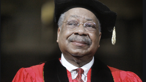 Clement Price is looking ahead smiling while wearing a graduation robe and cap