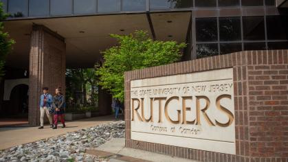Students walking near sign for the Rutgers Camden campus