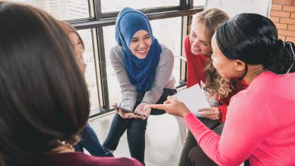 Women from diverse background sitting on chairs smiling and talking