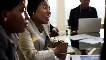 A diverse group of faculty talking in a conference room. An african american woman smiling is in focus.