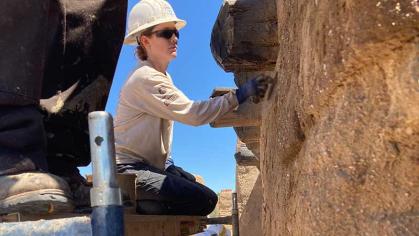 Johanna Cordasco kneels on scaffolding to apply an adobe mixture to a wall of Bent's Old Fort in southeastern Colorado, where AmeriCorps members worked to help restore the trading post.
