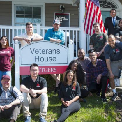 A multi-national group from of the Office of Veteran and Military Programs and Services standing in front of teh Veterans house smiling