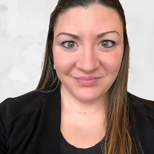 Christie Howley - A  caucasian woman with straight brown long hair looking ahead. She is smiling and wearing a black blouse and jacket and she is standing in front of a white background.