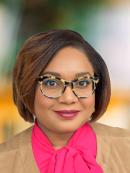 Francine Henry is wearing brown and black framed glasses with a pink blouse and tan jacket