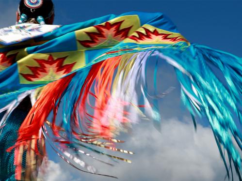 Closeup of the back of someone wearing colorful Native American traditional clothing that is blue, red, and yellow.