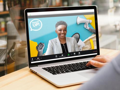 Closeup of a laptop screen with an african american woman with short hair on Zoom. She is standing in front of a blue background with black and white paper cutouts of raised fists in the air and hands holding bull horns