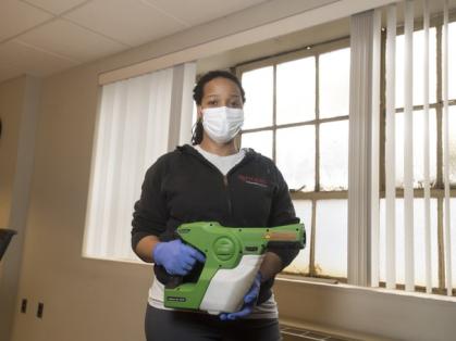 An female essential worker wearing a mask and holding a disinfecting sprayer