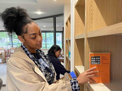 Jassadi Moore (left), a Rutgers graduate student, and undergraduate Stephanie Lopez-Perez (right) add books from Cheryl A. Wall’s collection to the shelves of the new reading room at the Paul Robeson Cultural Center dedicated to the late Rutgers professor.