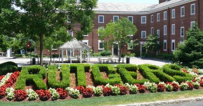 Picture of a flower bed with green hedging pruned in the shape of the word Rutgers